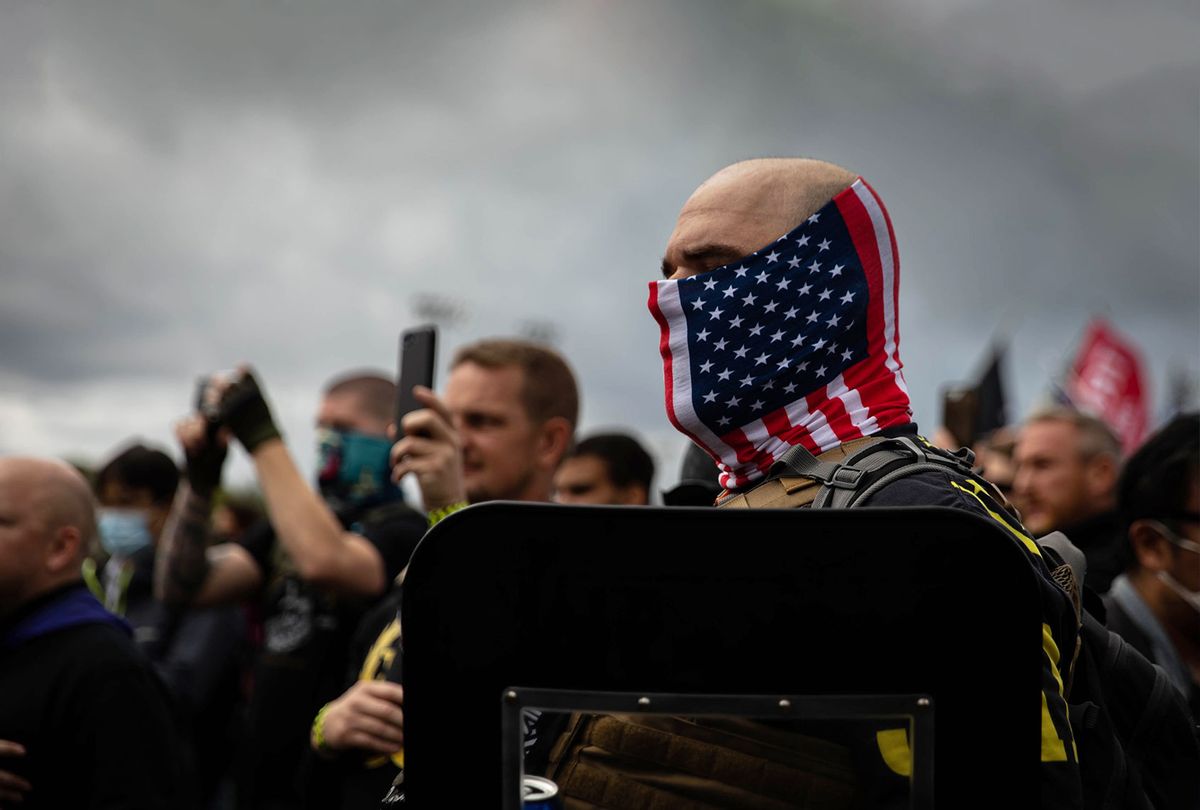 A man hold his hand to his heart as a Proud Boys organizer recites the Pledge of Allegiance during a Proud Boys rally at Delta Park in Portland, Oregon on September 26, 2020. (MARANIE R. STAAB/AFP via Getty Images)