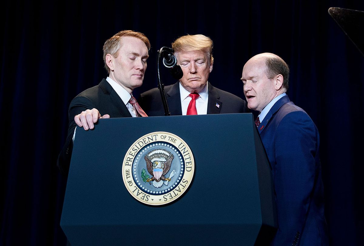 US Senator James Lankford (L) and US President Donald Trump (C) listen as US Senator Christopher Coons says a prayer during the National Prayer Breakfast on February 7, 2019 in Washington, DC. (BRENDAN SMIALOWSKI/AFP via Getty Images)