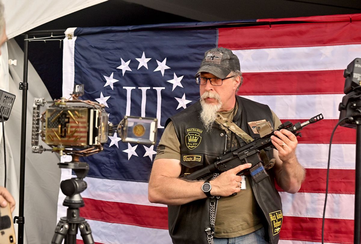 A man holding an automatic rifle poses in front of a 3% flag which is a far-right anti-government militia movement. The Rod of Iron Freedom Festival is an anti-government, Christian far-right movement that held a 3 day 2nd Amendment Rally of Freedom, Faith and Family. A few far right politicians were in attendance and the event featured a speech from HJ Sean Moon, the founder of the World Peace and Unification Church in Pennsylvania, who often wears a crown made of bullets. Members take marriage vows to their AR-15 rifles and have blessings for their guns. Many in attendance were seen carrying guns. (Aimee Dilger/SOPA Images/LightRocket via Getty Images)