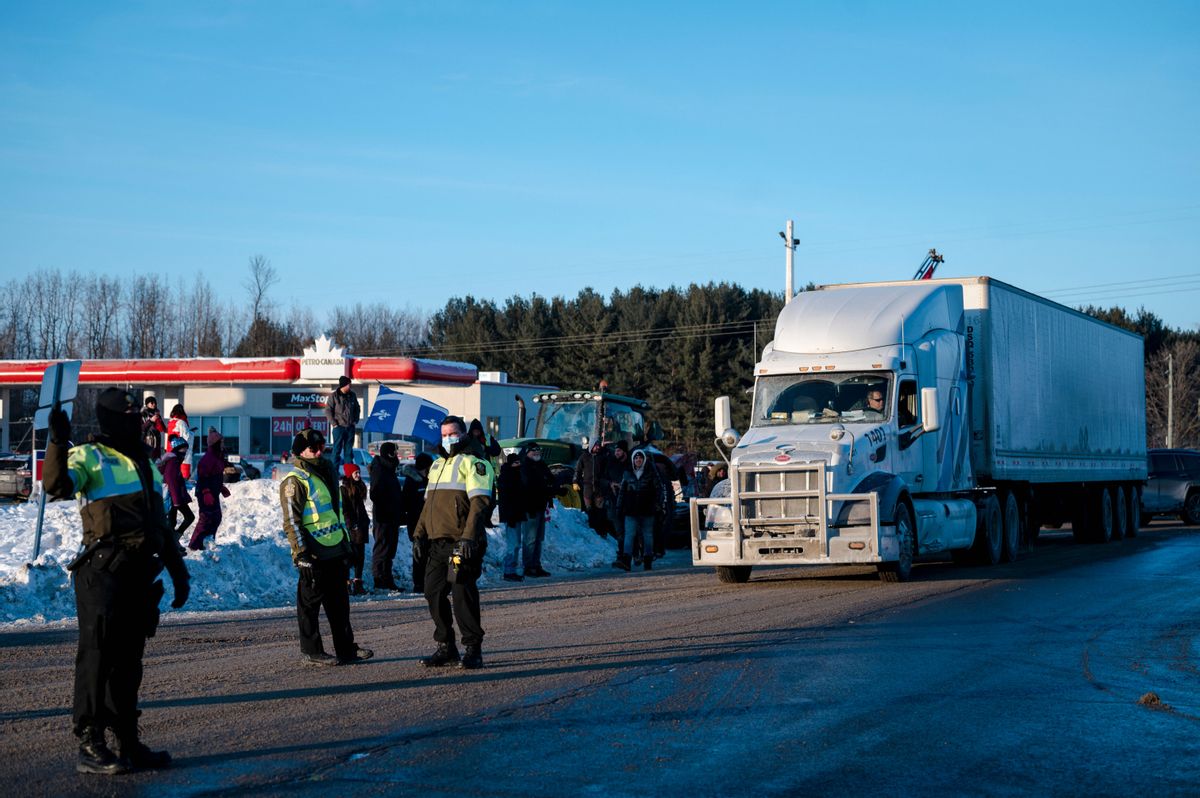 Police officers stop traffic as people gather along the Trans-Canadian highway to show support for the "Freedom Convoy," protesting against COVID-related mandates in Rigaud, Quebec, on Jan. 28. (Andrej Ivanov/AFP via Getty Images)