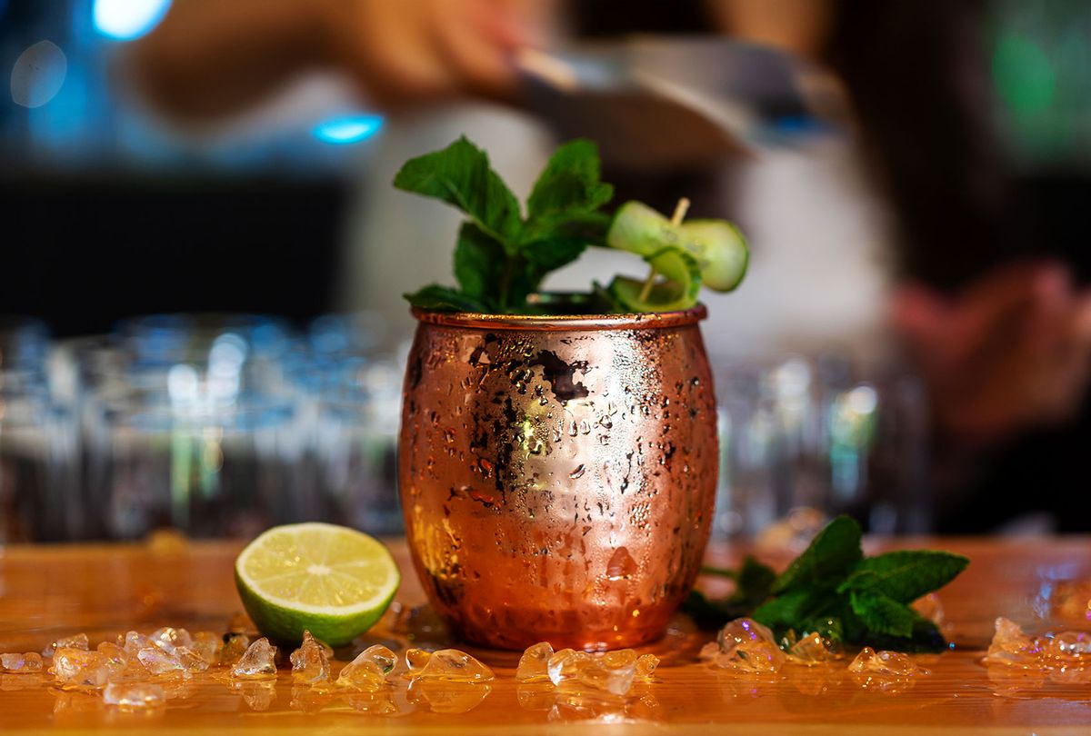 Moscow Mule cocktail served chilled with ice in a copper mug and garnished with fresh mint and lime on a wooden bar counter (Getty Images/Yulia-Images)