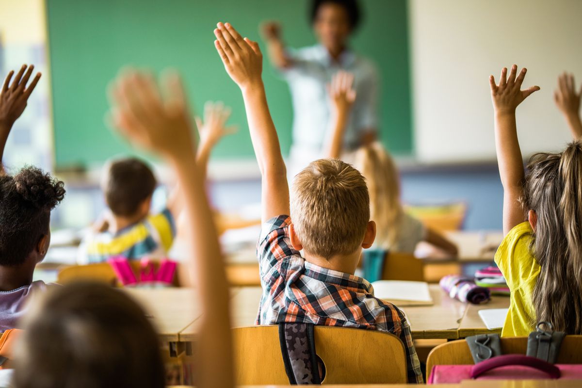 Rear view of large group of students raising their hands to answer the question on a class at elementary school.
 (Getty Images)