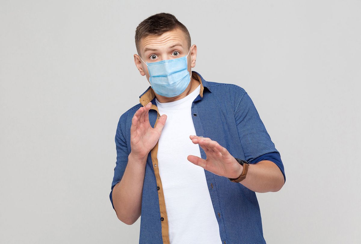 Scared young man in casual style with surgical medical mask  (Getty Images/Khosrork)