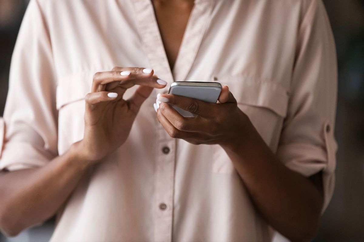 A woman holding a smart phone in her hand, typing a message. (Getty Images/fizkes)