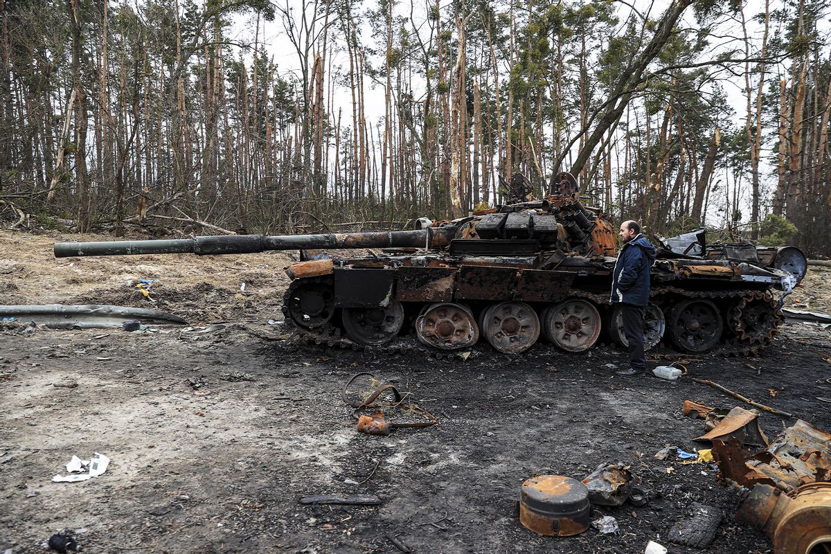 An unusable Russian tank and a man are seen on the Kyiv - Zhytomyr highway after the withdrawal of Russian forces and the recapture of the region by Ukrainian soldiers in Kyiv, Ukraine on April 05, 2022. (Metin Aktas/Anadolu Agency via Getty Images)