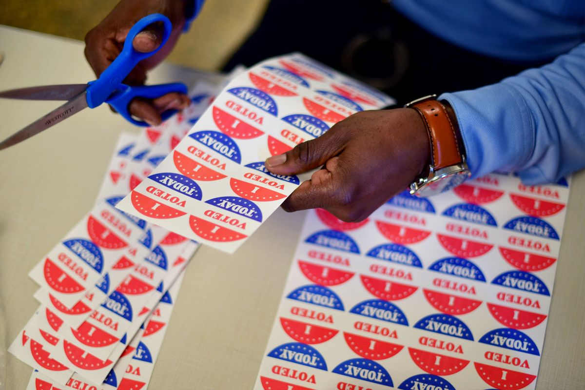 A volunteer cuts out "I VOTED TODAY" stickers for voters queueing outside of a satellite polling station on October 27, 2020 in Philadelphia, Pennsylvania. (Mark Makela/Getty Images)