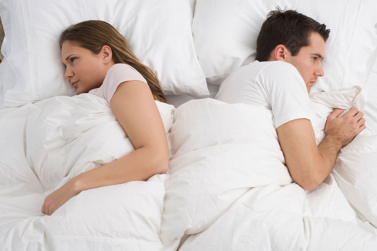 Angry couple laying in bed (Getty Images/Tetra Images)