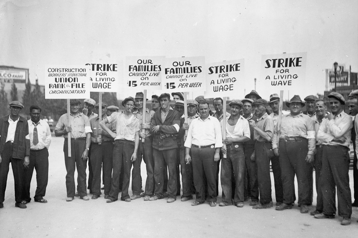 Full-length image of a group of strikers from the Construction Workers Union holding signs while picketing for higher wages.  (Lambert/Getty Images)