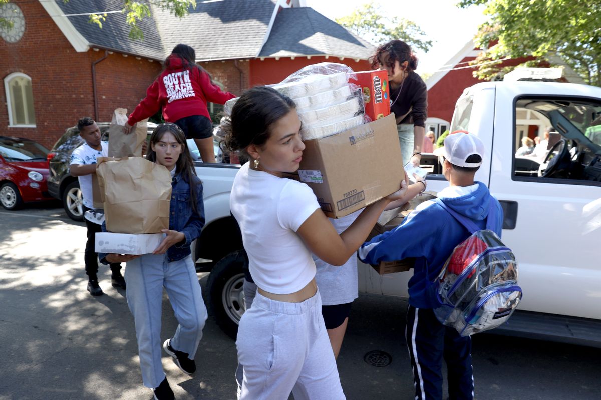 Students from the Martha's Vineyard Regional High School AP Spanish class help deliver food to St Andrew's Episcopal Church on Sept. 15. Two planes of migrants from Venezuela arrived suddenly on the island Wednesday night.  (Jonathan Wiggs/The Boston Globe via Getty Images)