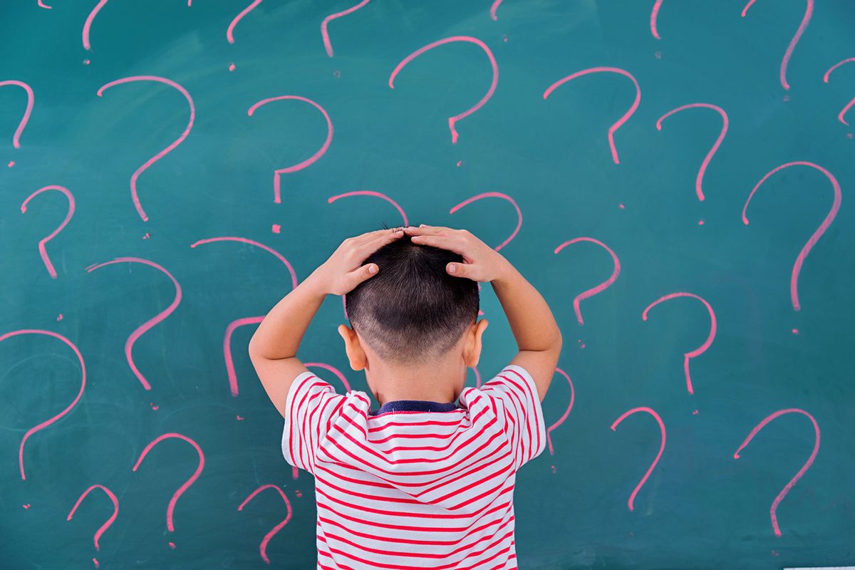 A little boy in front of blackboard with question marks (Getty Images/baona)