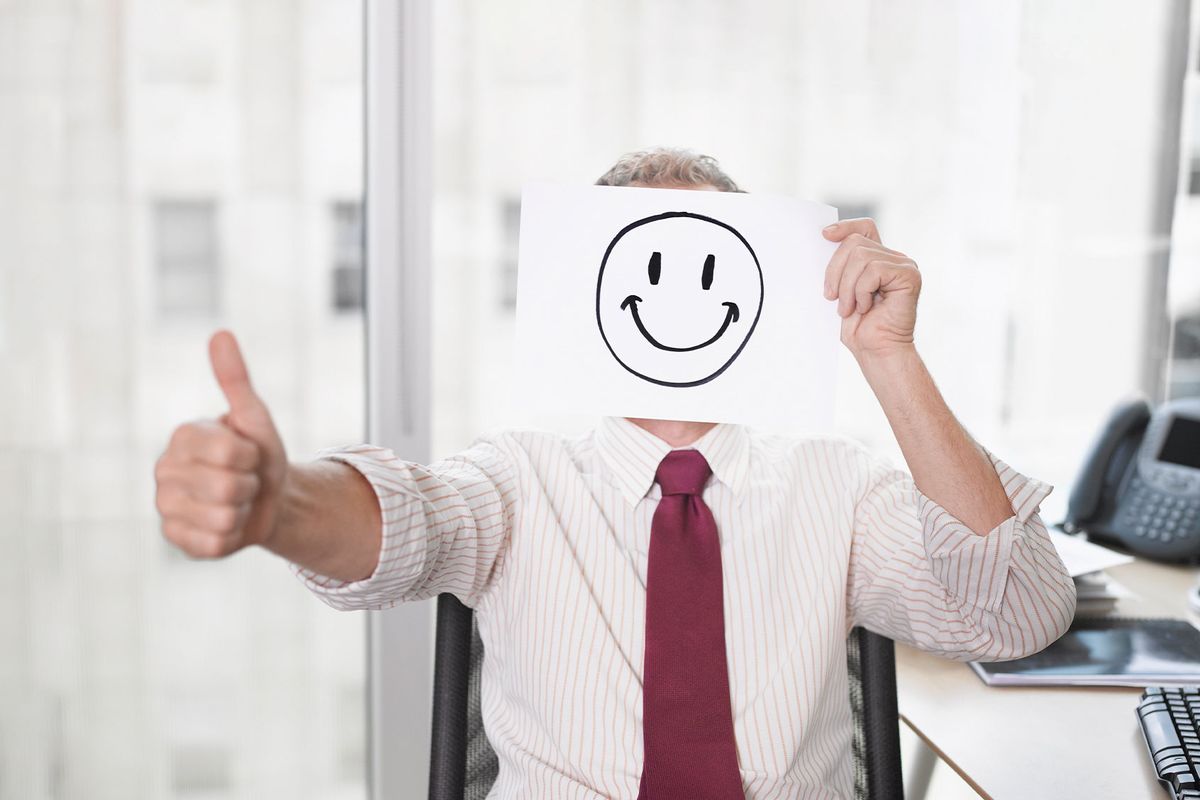 Businessman holding picture of happy face (Getty Images/Robert Daly)