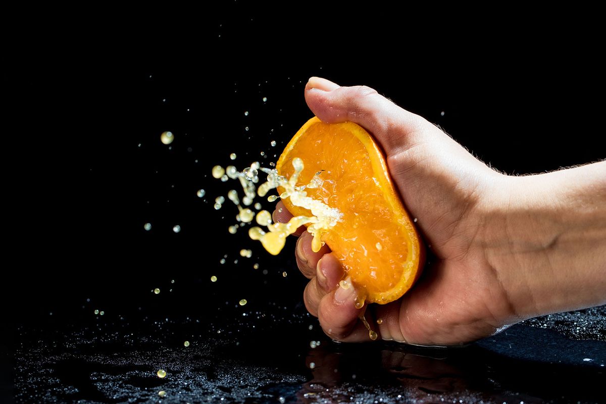 Hand squeezing an orange (Getty Images/zoranm)