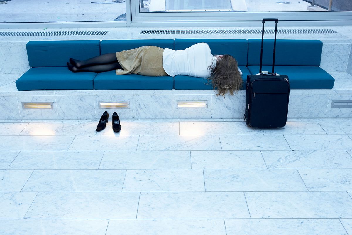 Woman sleeping on bench in airport (Getty Images/Jakob Helbig)