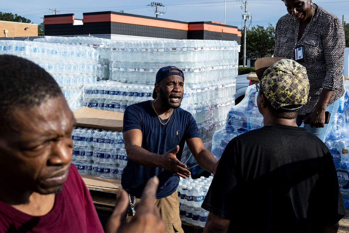 Jabari Omari, a Jackson city employee, talks with a resident while helping hand out cases of bottled water at a Mississippi Rapid Response Coalition distribution site on August 31, 2022 in Jackson, Mississippi. (Brad Vest/Getty Images)