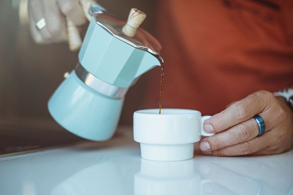 Man pouring coffee from a moka pot into a cup (Getty Images/NuriaE)