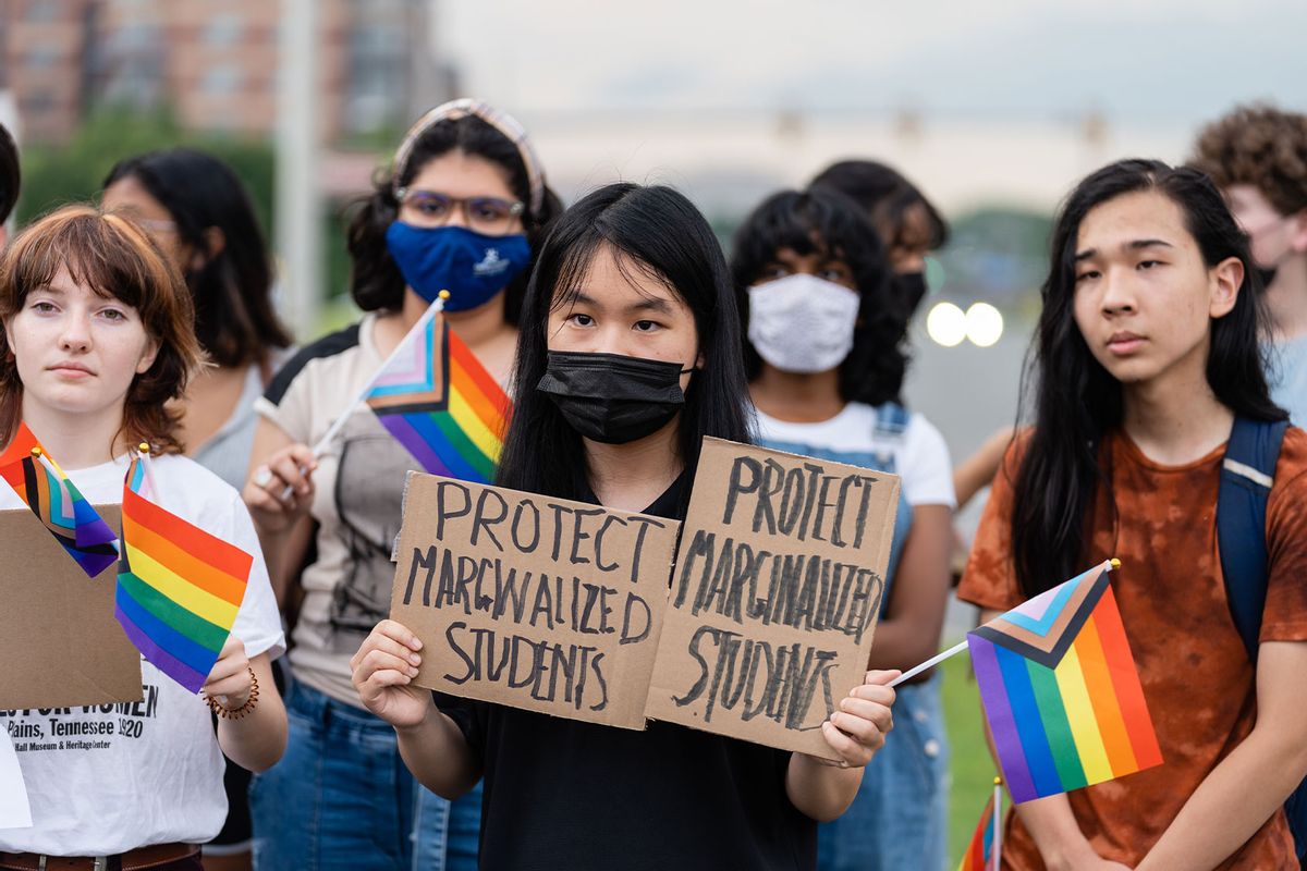A student holds signs during a rally in support of LGBTQ student rights in Falls Church, Va. on July 14, 2022 (Eric Lee for The Washington Post via Getty Images)