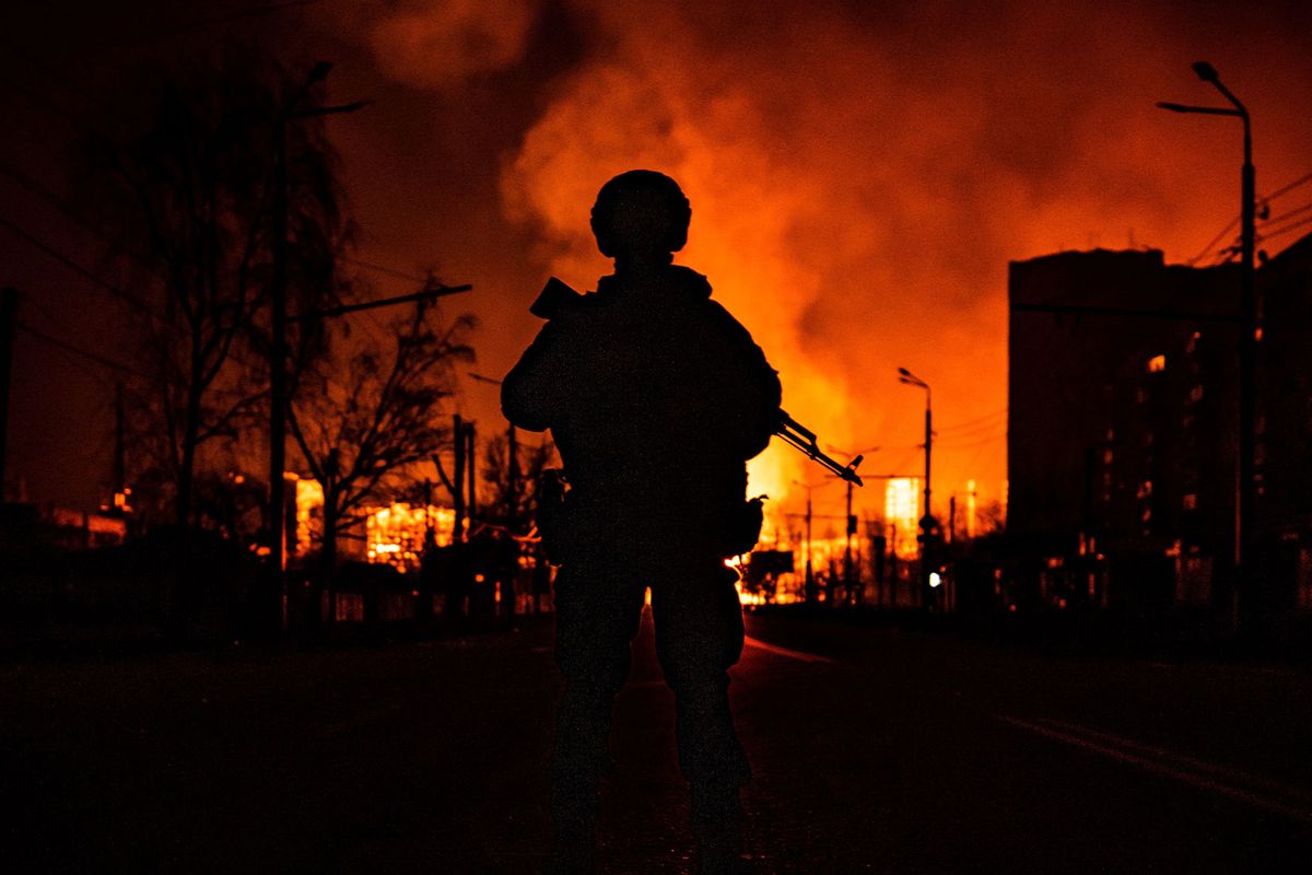A member of the Ukrainian special forces is seen in silhouette as he stands while a gas station burns after Russian attacks in the city of Kharkiv on March 30, 2022, during Russia's invasion launched on Ukraine. (FADEL SENNA/AFP via Getty Images)
