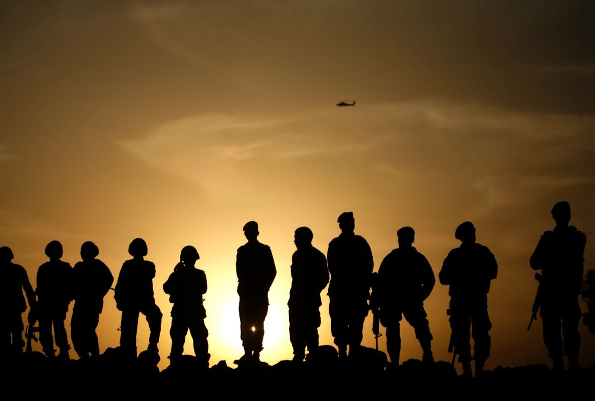 Afghan army commandos stand on a sand bank as a US Apache helicopter flies above on February 24, 2010.  (PATRICK BAZ/AFP via Getty Images)