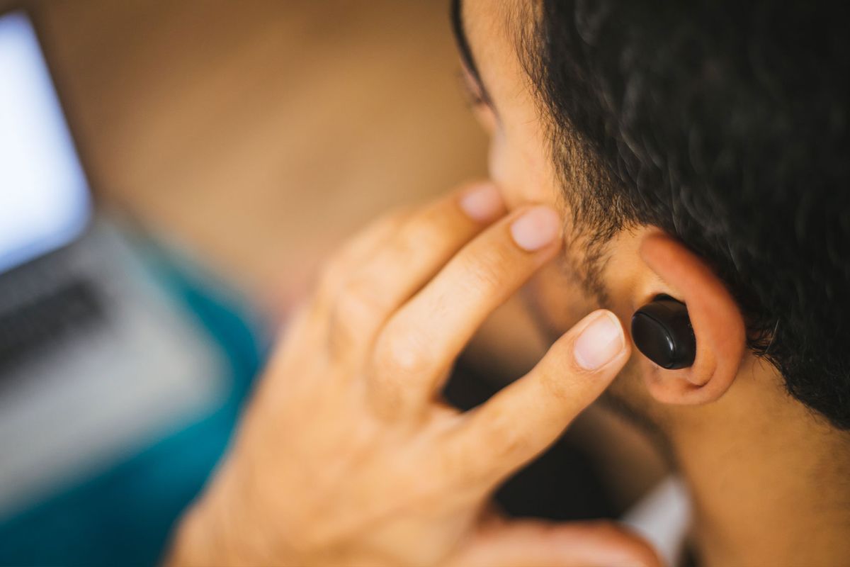 Man pushing in headphone earbud (Getty Images/agrobacter)