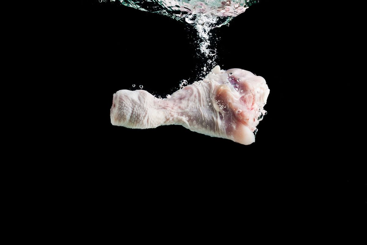 Chicken leg falls into the water on a black background (Getty Images/andreygonchar)
