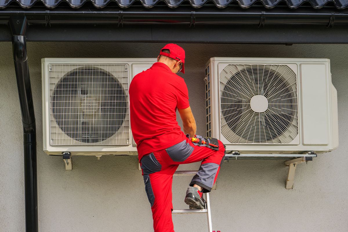 Heating and Cooling Technician Performing Scheduled Heat Pump Unit Service (Getty Images/welcomia)