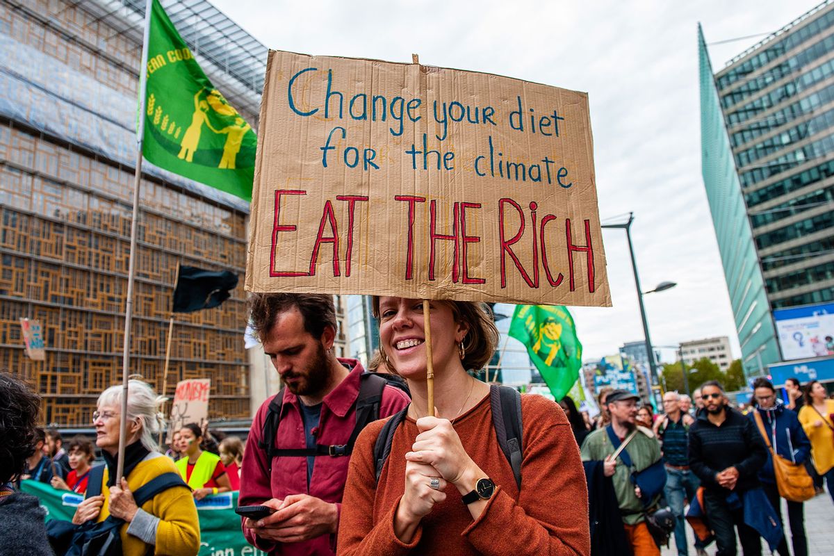 A protester holds a placard against the people with money during the climate change demonstration march.  (Ana Fernandez/SOPA Images/LightRocket via Getty Images)
