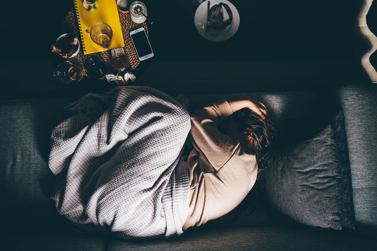 Sad woman lying on sofa at home (Getty Images/Maria Korneeva)