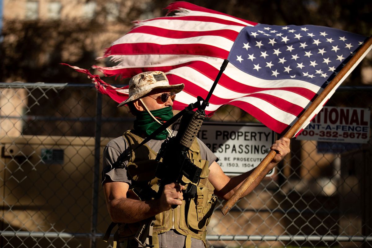 A supporter of President Trump holds a flag and gun outside the Arizona State Capitol on January 20, 2021 in Phoenix, Arizona. (Courtney Pedroza for the Washington Post/Getty Images)
