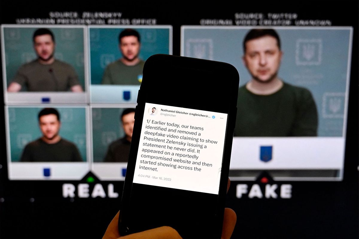 This illustration photo taken on January 30, 2023 shows a phone screen displaying a statement from the head of security policy at META with a fake video (R) of Ukrainian President Volodymyr Zelensky calling on his soldiers to lay down their weapons shown in the background, in Washington, DC. (OLIVIER DOULIERY/AFP via Getty Images)