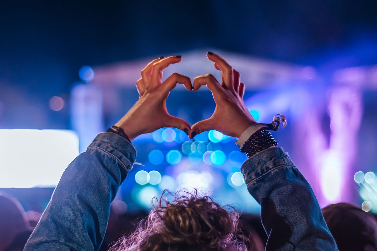 Woman making heart shape with hands at music event (Getty Images/Antonio Suarez Vega)