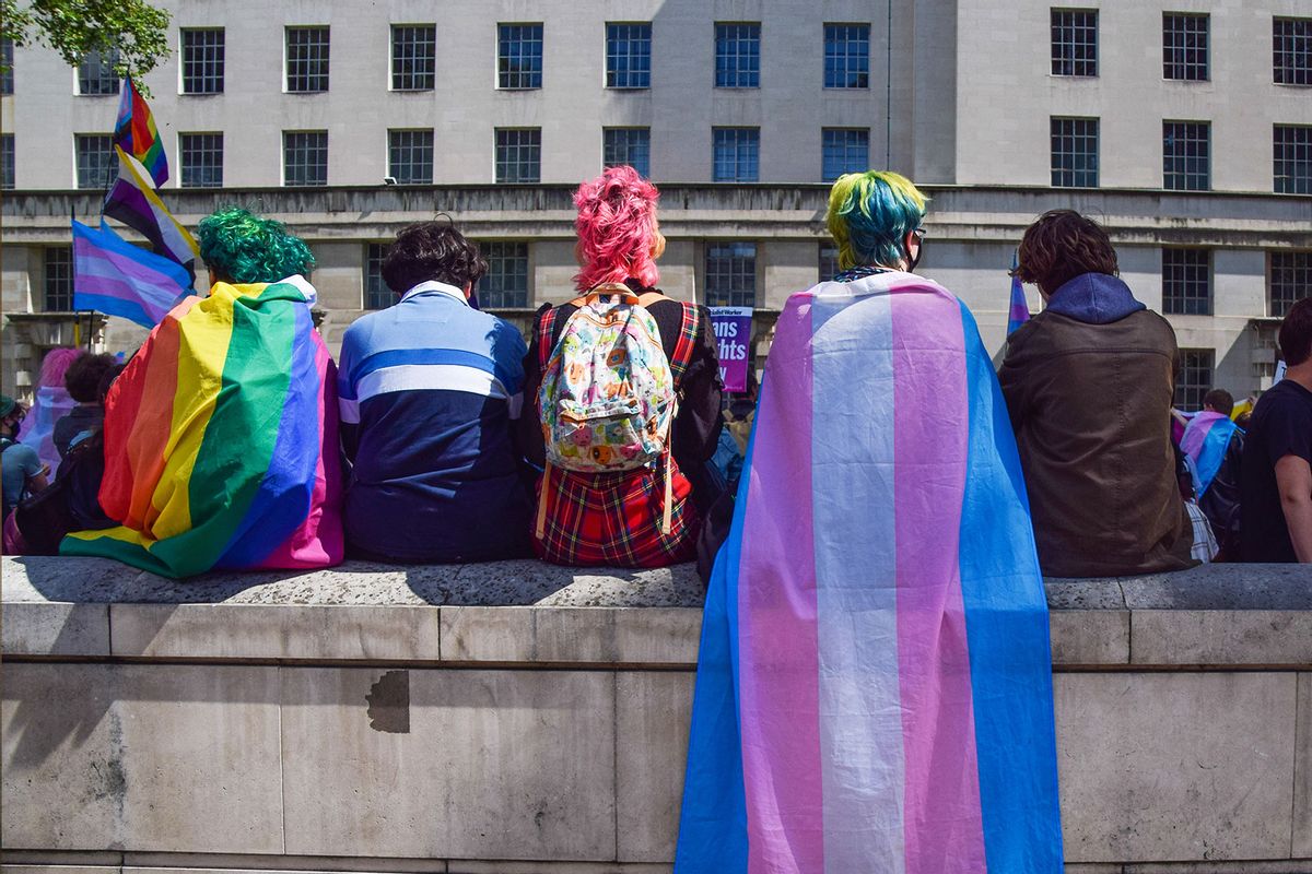 Protesters wrapped in pride and trans pride flags sit on a wall during a trans rights demonstration. (Vuk Valcic/SOPA Images/LightRocket via Getty Images)
