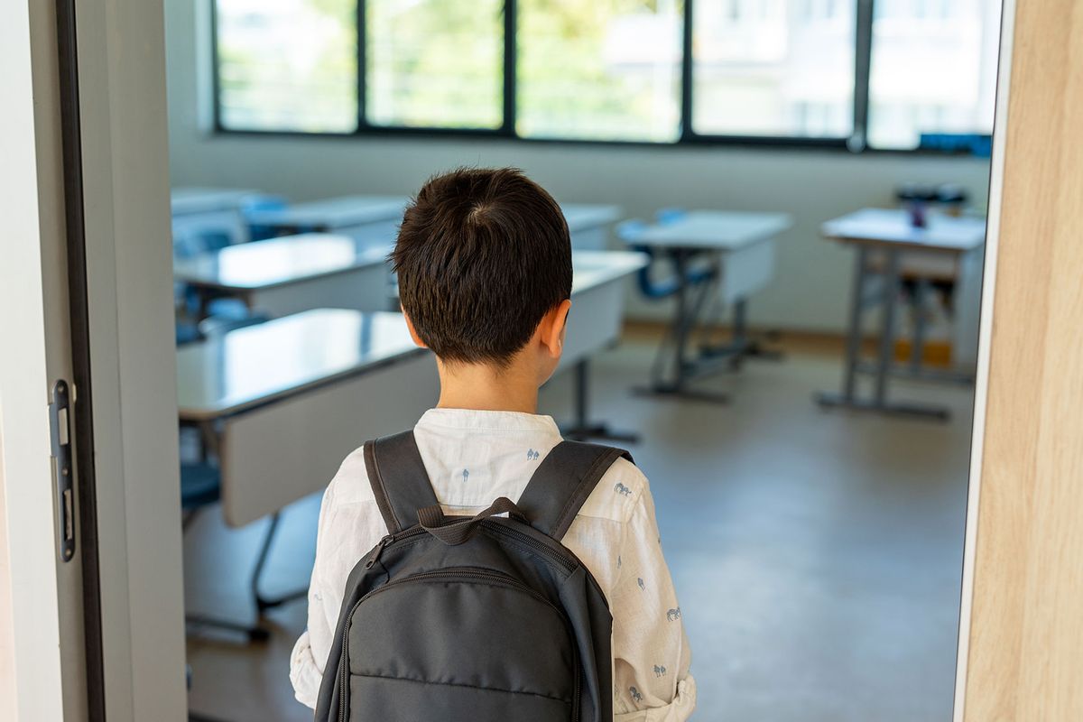 Schoolboy with backpack entering classroom (Getty Images/bymuratdeniz)