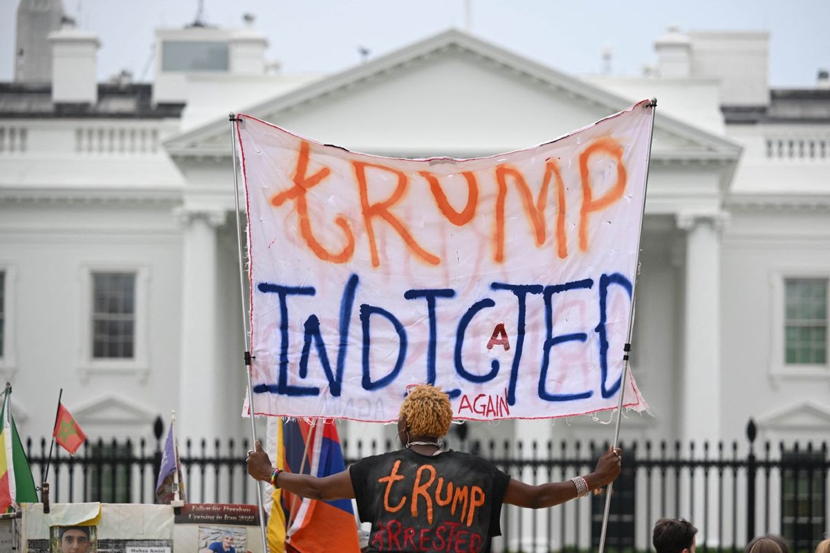 A woman celebrating the indictment of Donald Trump holds a banner in front of the White House in Washington, DC, on June 9, 2023.  (MANDEL NGAN/AFP via Getty Images)