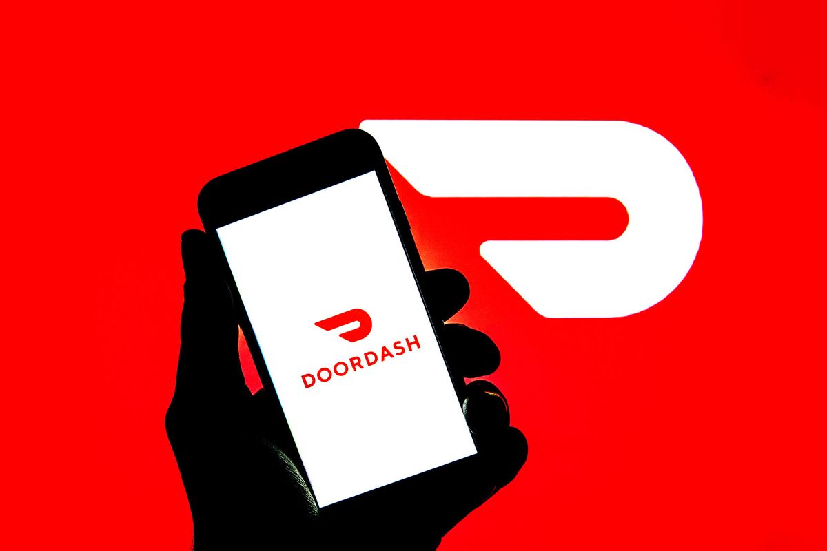 DoorDash logo seen displayed on a smartphone and on the background. (Photo Illustration by Thiago Prudencio/SOPA Images/LightRocket via Getty Images)