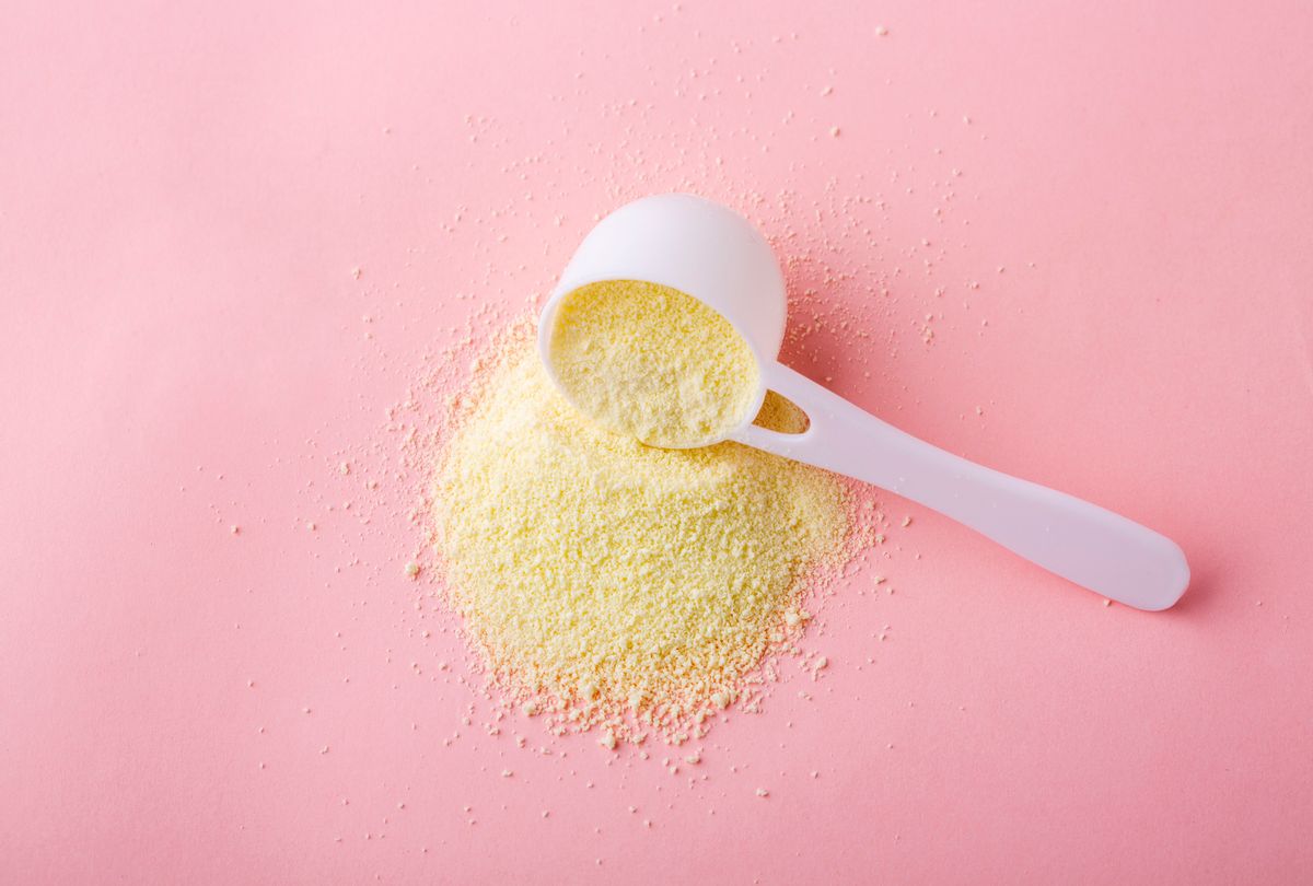 Powdered milk in plastic spoon on pink background (HUIZENG HU via Getty Images)