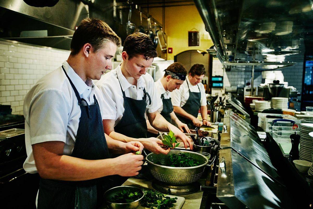 Kitchen staff preparing organic greens for dinner service on the line in a restaurant kitchen (Getty Images/Thomas Barwick)