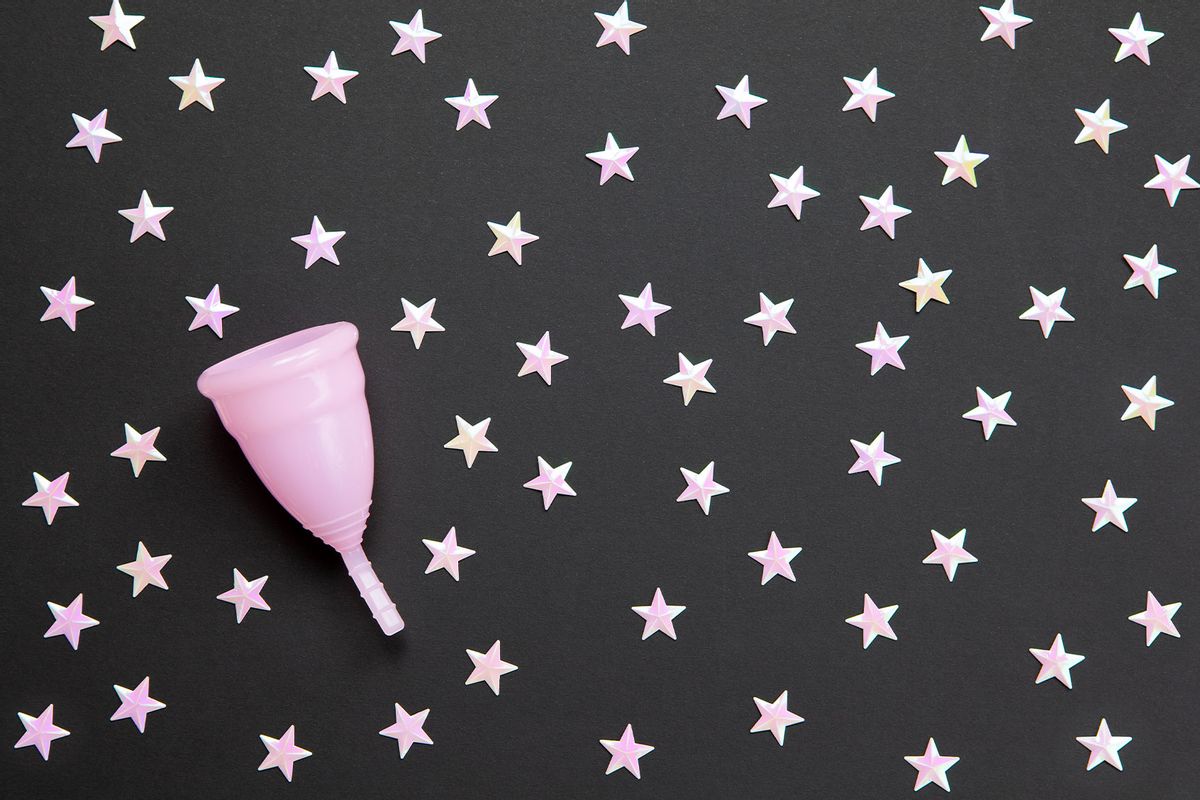 Pink menstrual cup against black background with stars (Getty Images/TatianaMagoyan)