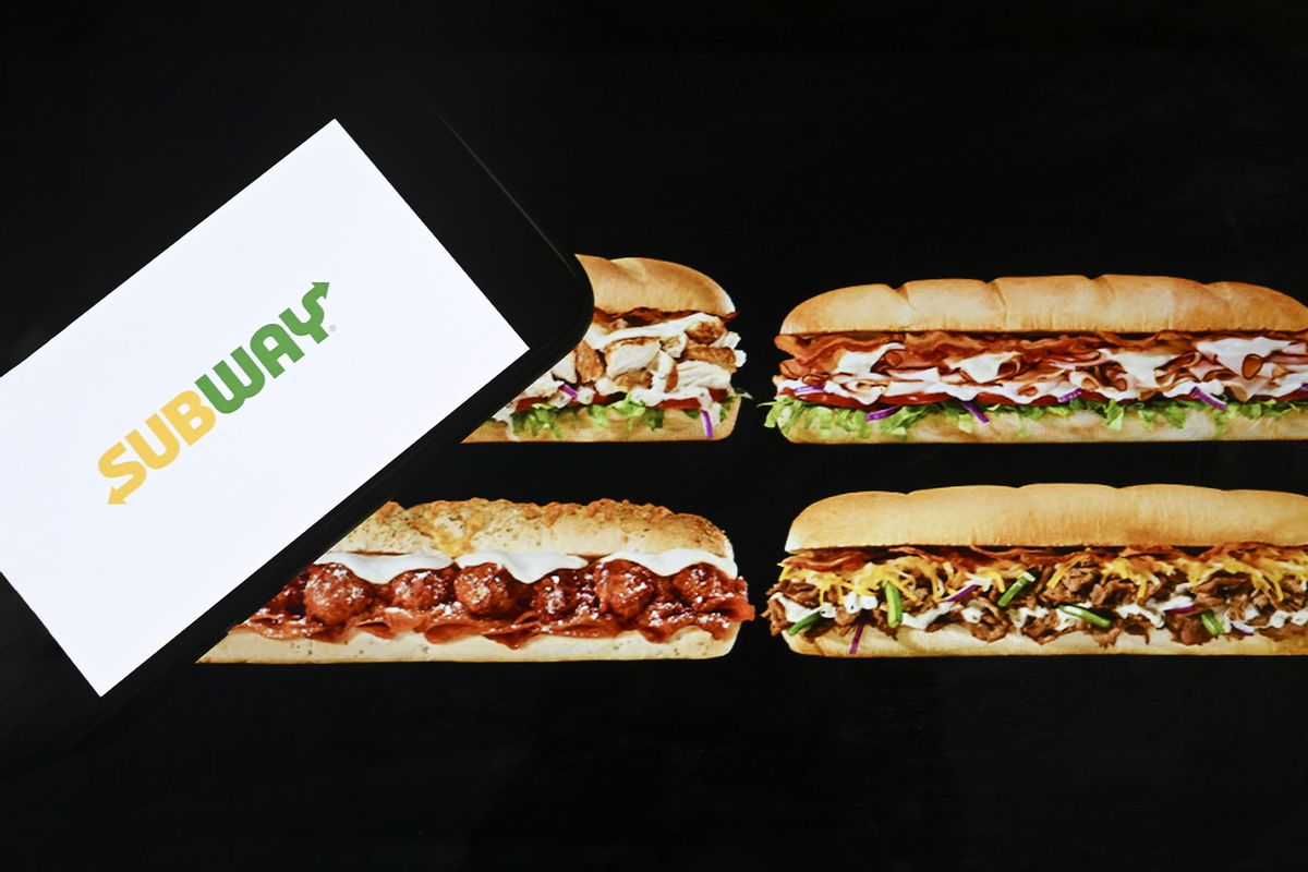 Logo of "Subway" is displayed on a mobile phone screen in front of sandwiches (Photo by Emin Sansar/Anadolu Agency via Getty Images)