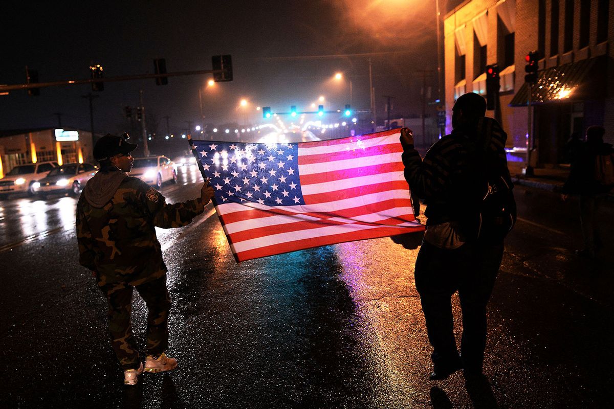 Two demonstrators march with a US flag in St. Louis, Missouri, on November 23, 2014 to protest the death of 18-year-old Michael Brown. (JEWEL SAMAD/AFP via Getty Images)