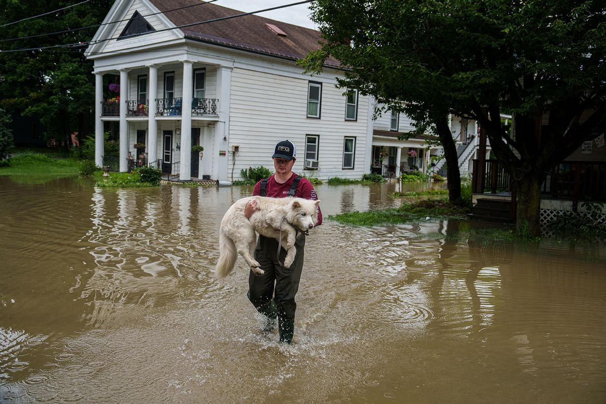 Tyler Jovic, of Montpelier, carries his neighbor's dog to dry ground on Tuesday afternoon, July 11, 2023. Vermont has been under a State of Emergency since Sunday evening as heavy rains continued through Tuesday morning causing flooding across the state.  (John Tully for The Washington Post via Getty Images)
