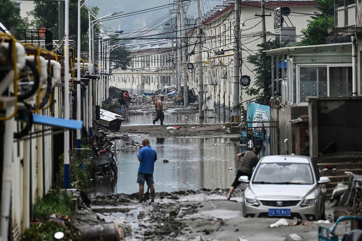 Local residents clean up the street in the aftermath of the flooding at a village following heavy rains in Beijing on August 3, 2023. (JADE GAO/AFP via Getty Images)