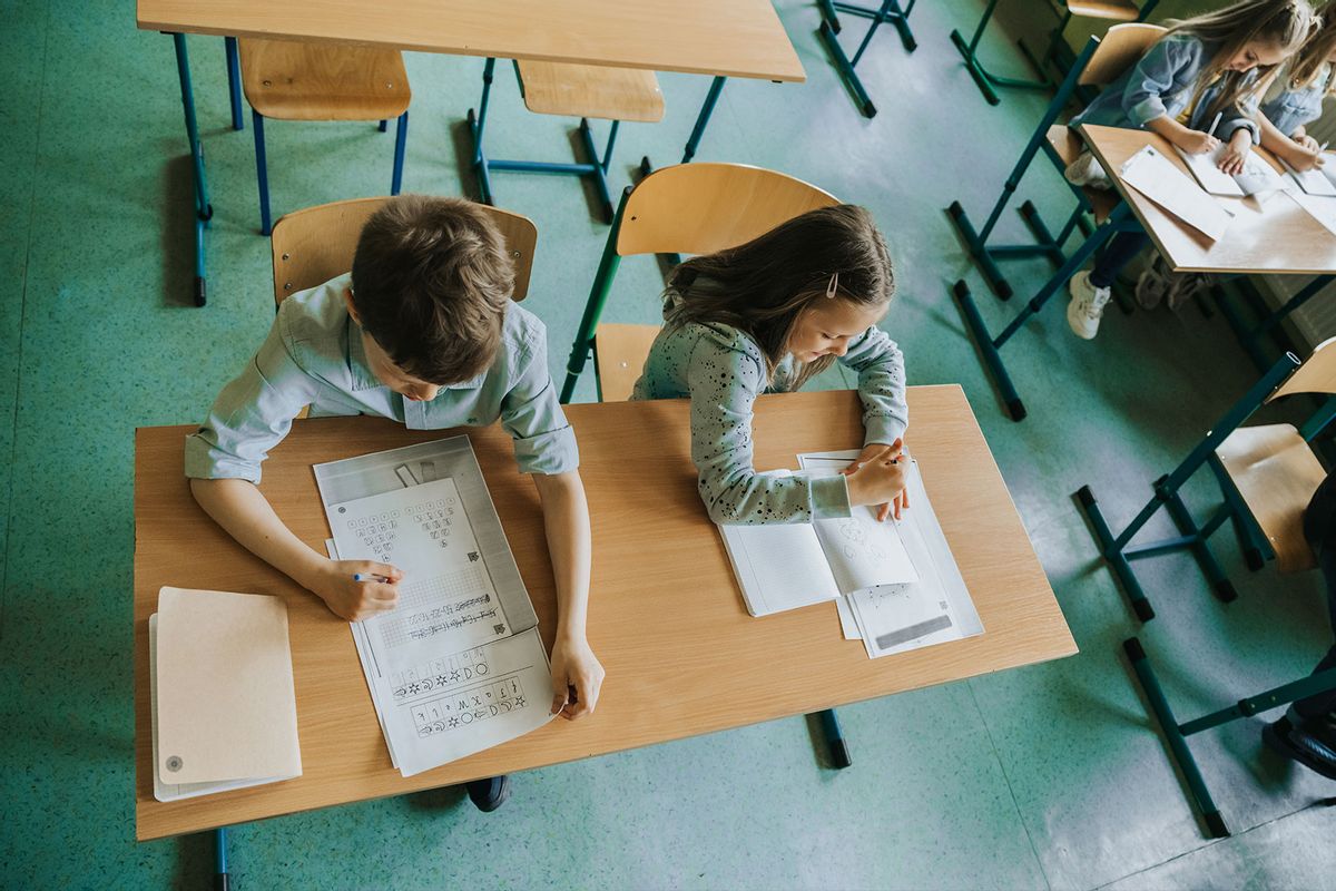 Overhead view on schoolboy and schoolgirl at school desk (Getty Images/golero)