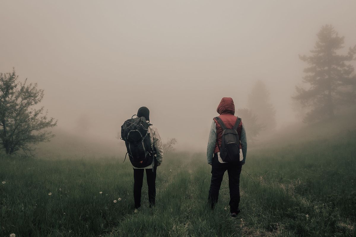 Campers hiking in a foggy field (Getty Images/rbkomar)