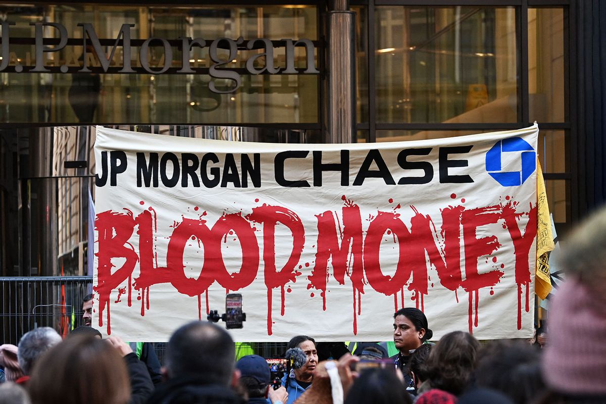 A banner is displayed as Indigenous and frontline land defenders and community members, who are directly impacted by extraction and destruction funded by JPMorgan Chase, demand that the bank stops all financing of fossil fuels during a protest outside the JPMorgan Chase Glasgow Headquarters in Glasgow on November 10, 2021, during the COP26 UN Climate Change Conference. (PAUL ELLIS/AFP via Getty Images)