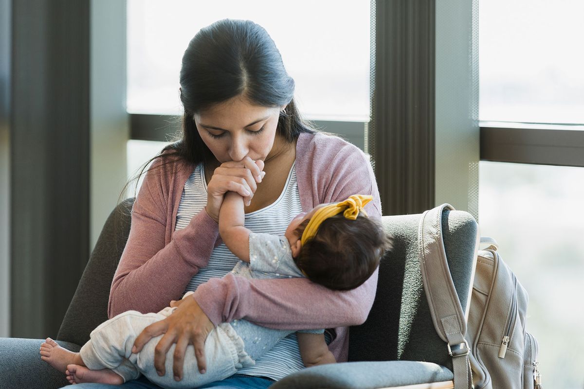 New mom closes her eyes as she kisses her baby's hand. (Getty Images/SDI Productions)