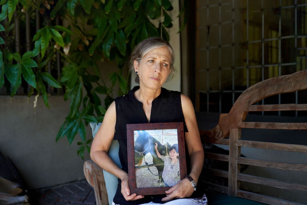 Deborah Blum holds a photo of her teen, Esther Iris, at home in Los Angeles. Blum and her husband, Warren, lost Esther Iris to suicide in 2021. When it came time to write the death notice, Deborah Blum was open and specific about the mental health struggles that led to her child’s death. (LAUREN JUSTICE FOR KFF HEALTH NEWS)