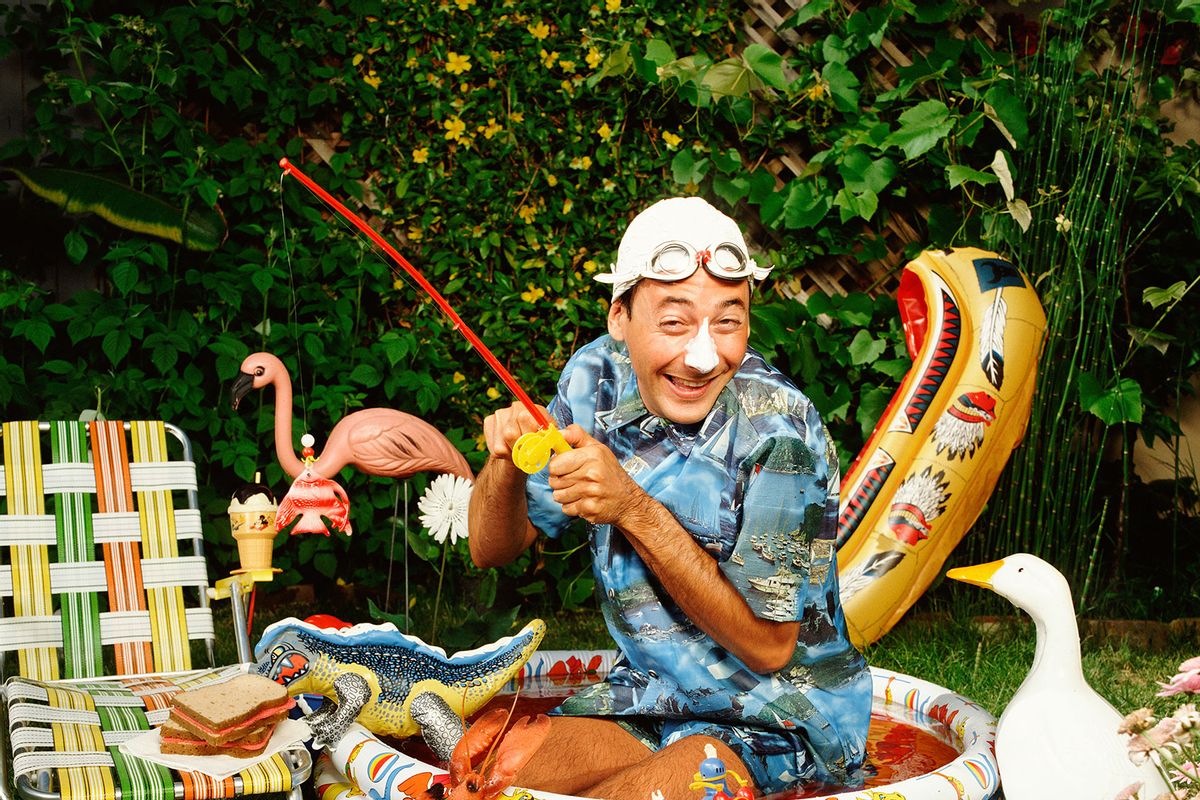 Pee-Wee Herman (Paul Reubens) kneels in a kiddie pool, wears a swim cap with goggles, and fishes with a plastic rod amongst scattered toys and plastic fish in Los Angeles in 1983. (Bonnie Schiffman/Getty Images)
