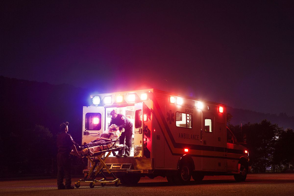 Paramedics carrying patient in ambulance at night (Getty Images/Cavan Images)