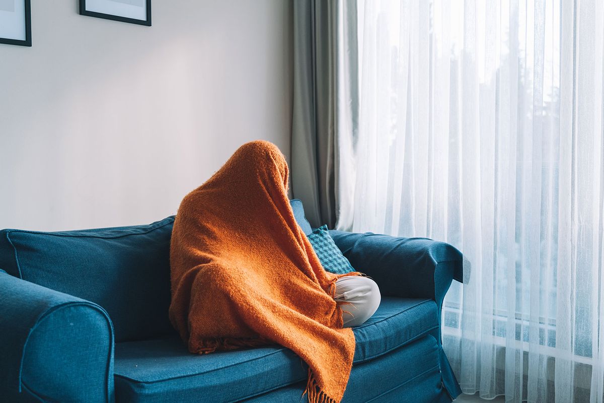Person hiding in an orange blanket (Getty Images/Olga Rolenko)