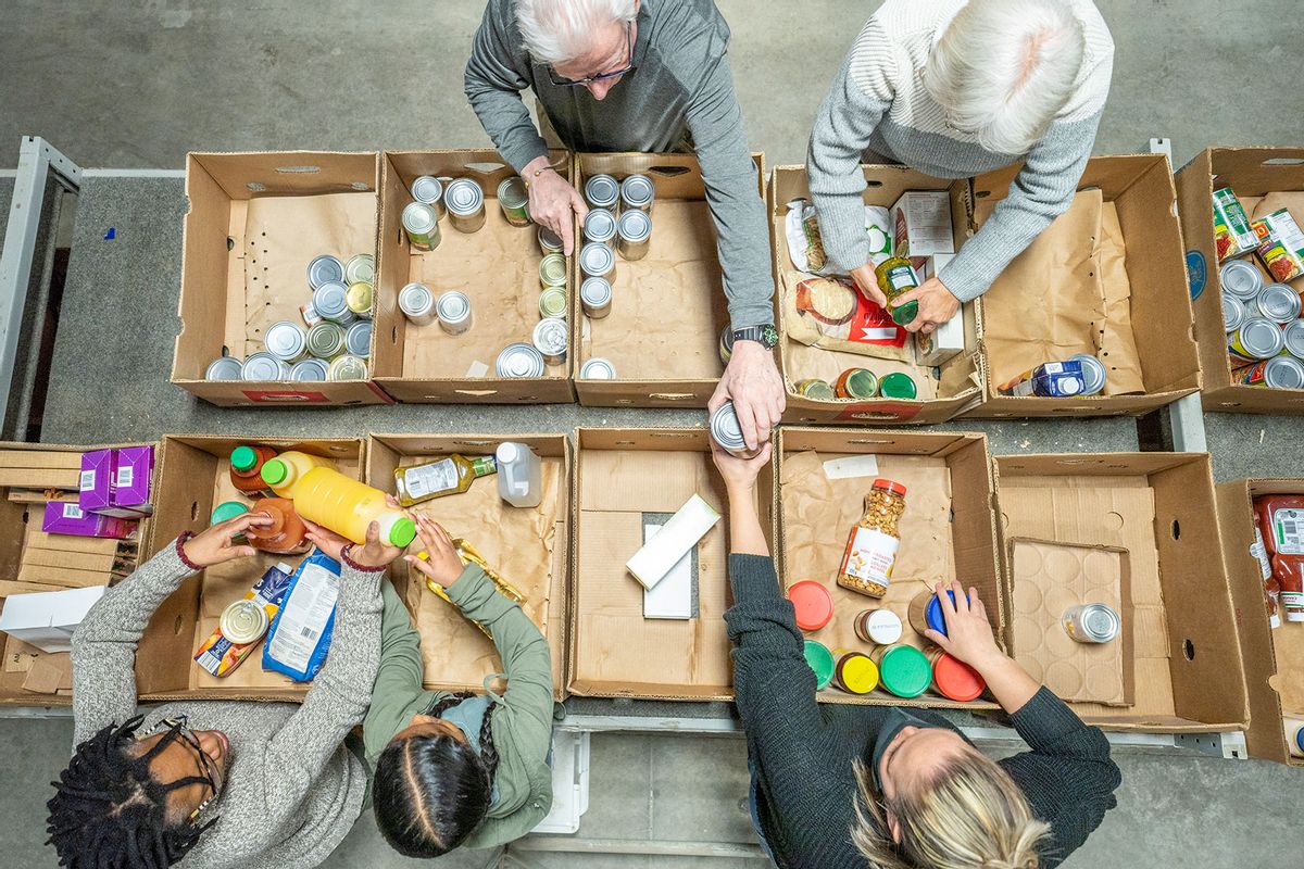A small group of volunteers of various ages are seen packing and sorting cardboard boxes of non-perishable food items as they give of their time to a local Food Bank. (Getty Images/FatCamera)
